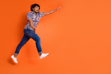 Full size photo of nice young man running stretch hands wear trendy colorful outfit isolated on orange color background