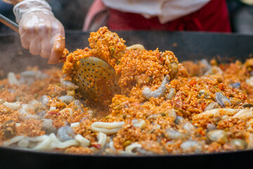 Close up of traditional Spanish paella being cooked and prepared in a big pan