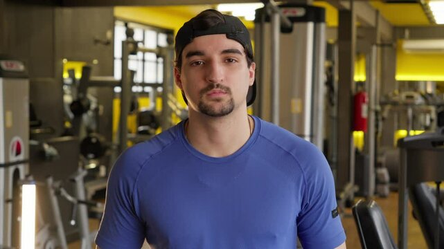 Portrait of a Man in a Gym. Focused Gym-Goer in a Blue Shirt Looking Intently at the Camera, Set in a Modern Fitness Environment