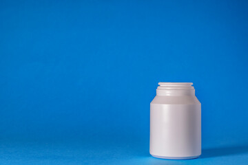 White pill container, tablet bottle isolated on a blue background. pure, medical concept, pharmacy theme. copy space.