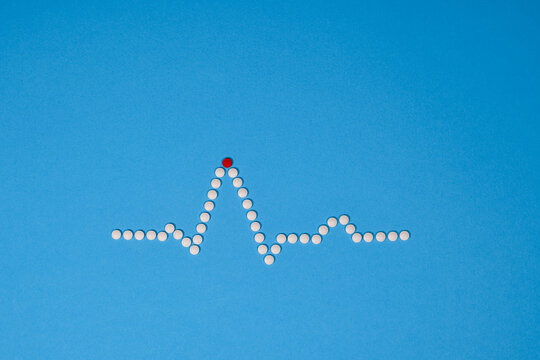 ECG wave, made of tablets, pills, against a blue background. PQRST sinus rhythm in white tablets. Clinical image editorial medical heart related picture. EKG cardiac trace.