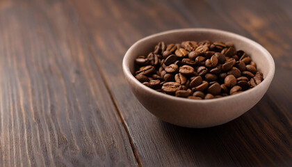 Fototapeta premium Roasted coffee beans in ceramic bowl on dark wooden table. Tasty and aromatic beverage.