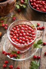 A cup of herbal tea with fresh hawthorn berries harvested in autumn