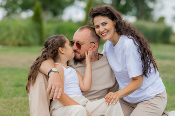 happy family is relaxing on a green lawn in the park in summer