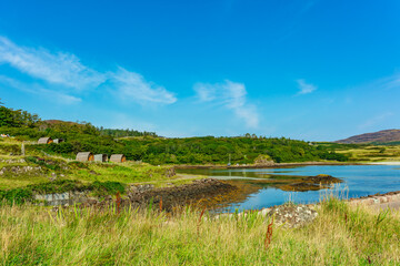 The beautiful Isle of Eigg in Summer with Eigg camping pods overlooking the bay and pier.  the Isle of Eigg is situated in the Inner Hebrides, Scotland and is a community owned island. Space for cop