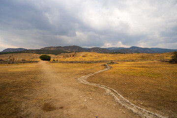 Hierapolis in Pamukkale: A desolate path winds through the arid landscape, leading towards ancient...