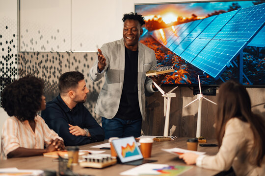Diverse ecologist with solar panel model having briefing with eco team