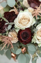 Fototapeta premium Beautiful arrangement of red and cream roses with greenery and touches of gold in a bouquet