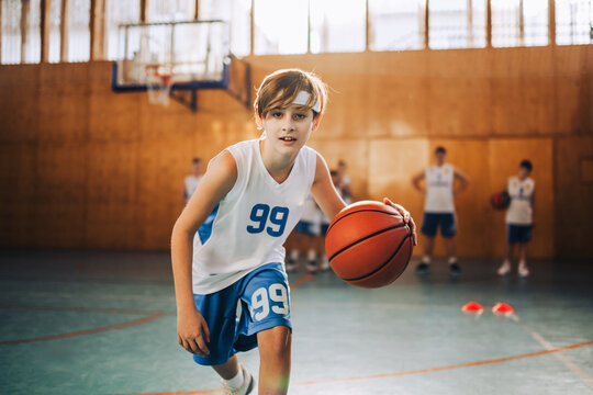 Active young player dribbling basketball in gym