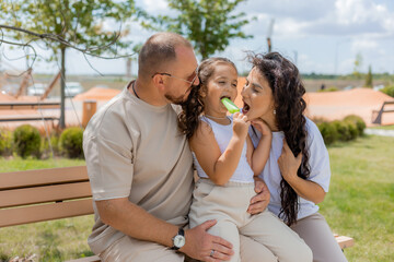 Naklejka premium A happy family is relaxing in the park and eating ice cream