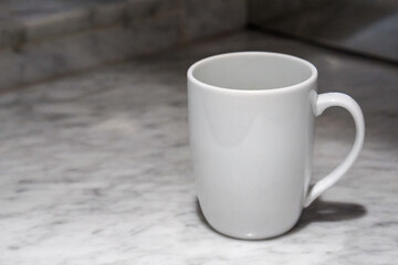 Obraz premium A white coffee cup sits on a marble table.