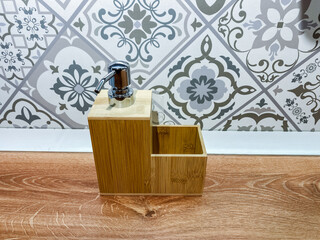 A charming wooden soap dispenser sits elegantly on a beautifully polished wooden floor, significantly enhancing the overall aesthetic appeal of the space in front of a stylishly tiled wall