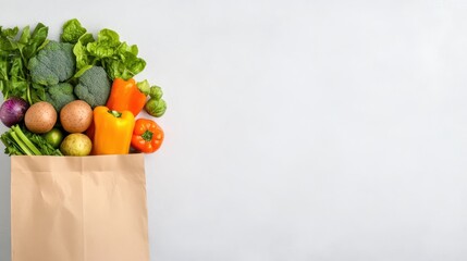 Brown paper bag filled with fresh vegetables, including broccoli, bell peppers, and potatoes, isolated on a white background. Grocery shopping concept.