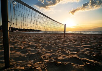 Volleyball net on sandy beach at sunset, with blurry silhouettes of people and ocean in background