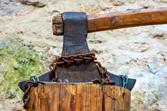 A historical ax stuck in a tree stump is the working tool of an executioner from the Middle Ages