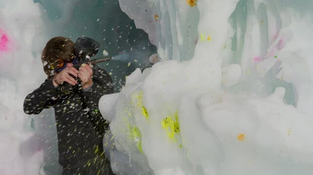 Paintballs bouncing off ice structure as man fires his own gun back - slow motion
