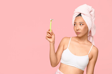 Thoughtful young Asian woman with razor on pink background