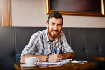 Portrait, man and owner with documents at cafe for writing finance planning, vendor contract and inventory budget. Person, paperwork and smile with feedback form, sales profit and business growth