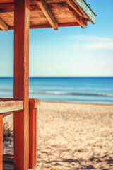 Obraz premium Close up of lifeguard house on empty sandy beach at autumn. The end or final of the beach season
