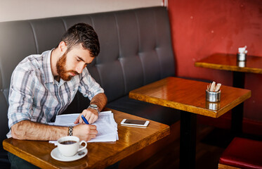 Business, owner and writing with documents at cafe for finance planning, vendor contract and inventory budget. Male person, paperwork and customer feedback form, sales profit and reading information