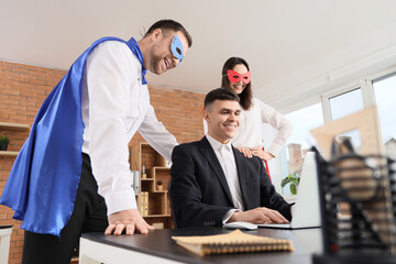 Business people dressed as superheroes working in office © Pixel-Shot
