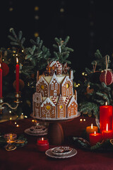 Family holiday celebration. Beautiful traditional homemade gingerbread house. Celebration of Christmas and Happy new year at home. Festive mood, cozy atmosphere, burning candles, fir tree branches