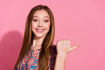 Photo of toothy beaming girl with straight hair wear print t-shirt directing at proposition empty space isolated on pink color background