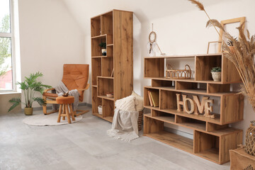 Interior of living room with armchair, shelf units and Tibetan bowl on pouf