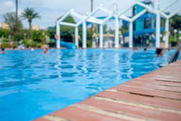 low angle closeup view of tropical hotel swimming pool with blurred people in the background