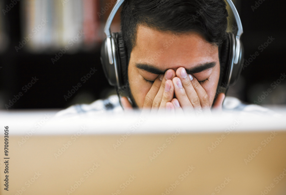 Poster Man, university student and exhausted on computer with headphones in library for internet, online error and research. Male person, tired and burnout or headache with assignment deadline and study
