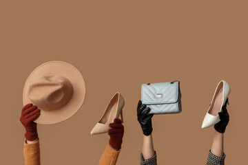 Female hands in gloves with bag, hat and heeled shoes on beige background