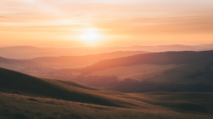 Fototapeta premium A sunset over rolling hills with the sun casting long shadows and the sky filled with soft pink and gold hues creating a tranquil and dreamy atmosphere.