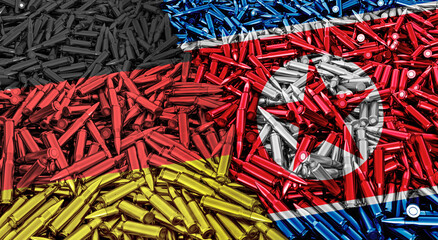 A large pile of bullets for automatic weapons in the shape of the flags of Germany and North Korea, concept of military conflict