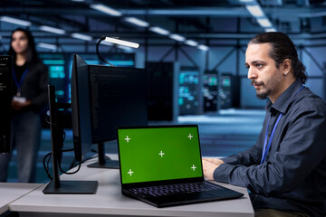 Engineer using green screen laptop to do maintenance in server hub, extending equipment life span....