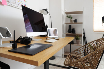 Table with modern computer, photo camera and gadgets in office. Photographer workplace concept