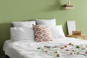 Soft bed with pillows and flowers in stylish bedroom