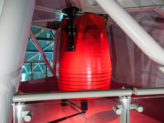Red tuned mass damper pendulum is installed on the top floor of a high-rise structure, designed to...