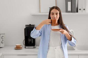 Beautiful young happy woman with cup of coffee having break at kitchen in office