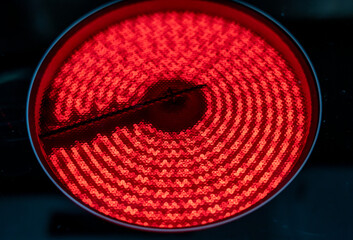 Close-up of a hob with electric hot plates: the heating elements are bright red. Selective focus on...