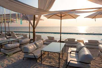 Beautiful luxury swimming pool on sea view and umbrella and chair in hotel resort with sunset.