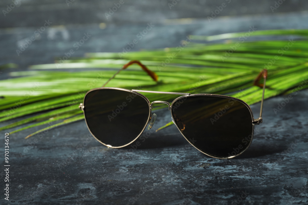 Wall mural stylish sunglasses and palm leaves on black grunge background