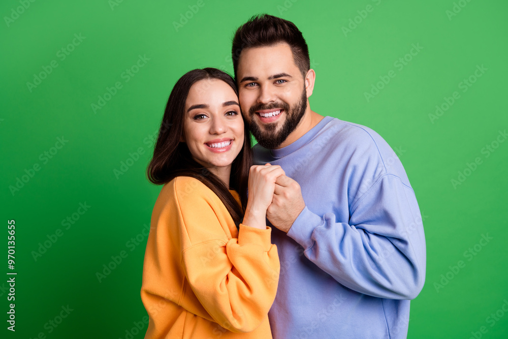 Poster Photo of positive lovely cute couple wear stylish clothes cuddling isolated on green color background