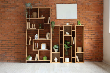 Shelving unit with houseplants and books near brown brick wall in room