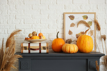 Suitcase, picture and pumpkins on fireplace in living room. Autumn concept