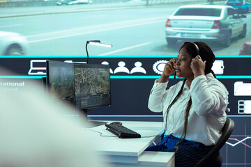 African american government employee monitoring traffic activity via surveillance footage on CCTV...
