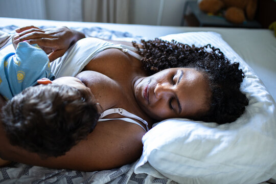 Mother breastfeeding baby in bed at home