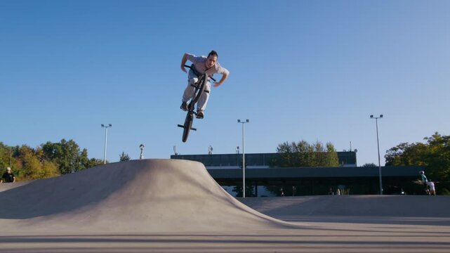 Hipster jumping over pipe with no hands on handlebars