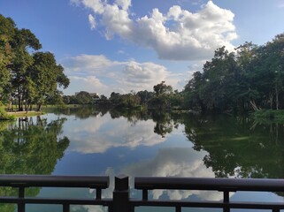 A serene lake in Chiang Mai, Thailand, with crystal-clear waters perfectly reflecting the blue sky...