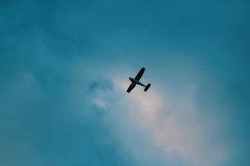 A single-engine airplane soars against a cloudy sky