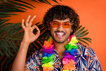Photo portrait of nice young man show okey enjoy summer palm leaves wear trendy colorful outfit isolated on orange color background